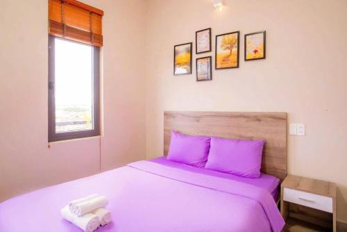 a bedroom with a bed with purple sheets and a window at Merci Đà Lạt Home in Da Thanh