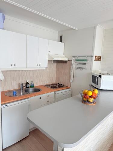 a kitchen with white cabinets and a bowl of fruit on a counter at Apt Ideal Famille Pied des pistes - 46m2 - 6 pers in Vars