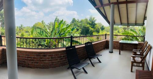 a balcony with two chairs and a view of trees at New Runaliya in Anuradhapura
