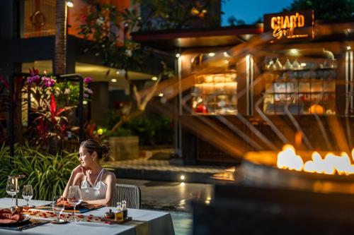 a woman sitting at a table in a restaurant at Avista Grande Phuket Karon - MGallery in Karon Beach