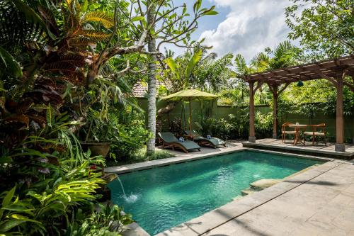 a swimming pool in a garden with a pergola at Arkamara Dijiwa Ubud in Ubud
