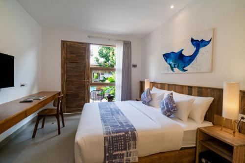 a bedroom with a bed and a desk and a window at Lakubumi Pavilion in Jimbaran