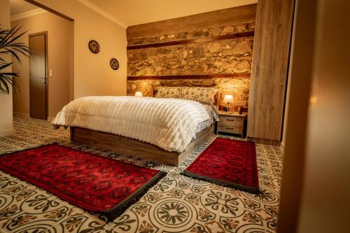 a bedroom with a bed and two red rugs at Σοχός Παραδοσιακές Οικίες- ΒΕΝΙΖΕΛΟΥ in Zokhós