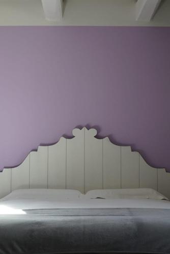 a bedroom with a bed with a purple headboard at Agriturismo Colle Casini Cortesi in Caldarola