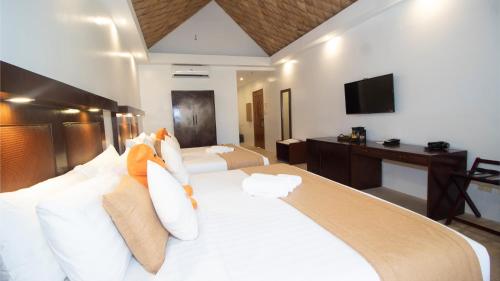 a bedroom with a large white bed with a television at Ambassador In Paradise in Boracay