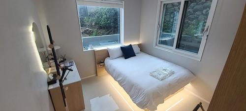 a small bedroom with a bed and two windows at Cony Ocean Suite Hotel in Jeju
