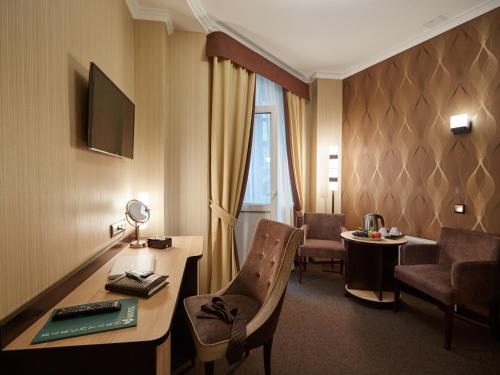 um quarto de hotel com uma secretária, uma mesa e cadeiras em Birch Yard Hotel em Rostov on Don