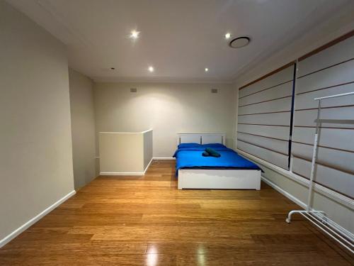 a bedroom with a blue bed and a wooden floor at 66 Red Room in Beecroft