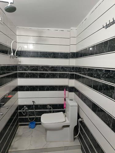 a bathroom with black and white tile walls and a toilet at Sunbeam Stay in Prayagraj