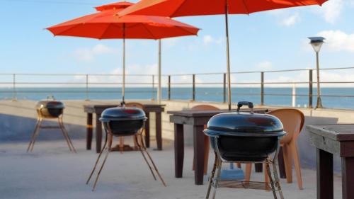 a table with a grill and umbrellas on the beach at Gangneung Glad Pension in Gangneung