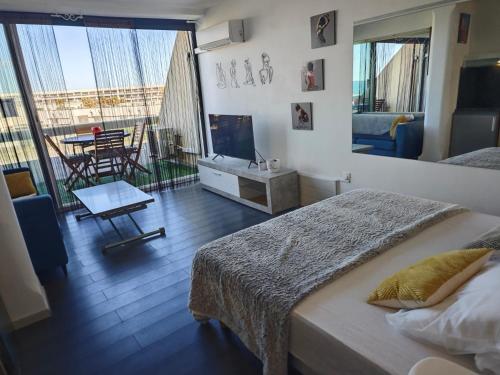 une chambre avec un lit et un balcon avec une table dans l'établissement Studio Village Naturiste Resille, au Cap d'Agde