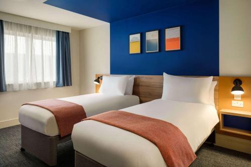 two beds in a hotel room with blue walls at Days Inn Chesterfield - Tibshelf in Chesterfield