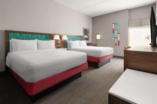 a hotel room with two beds and a desk at Hampton Inn Sturbridge in Sturbridge