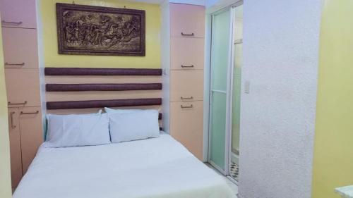 a bedroom with a white bed and a painting on the wall at Lovely house in Pagadian city in Norte