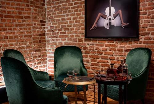 a room with green chairs and a brick wall at Hotel Saski Krakow Curio Collection by Hilton in Kraków