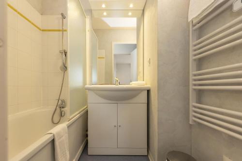 une salle de bain avec un lavabo, un miroir et une baignoire dans l'établissement Résidence Odalys Mille Soleils, à Font-Romeu