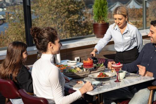 a woman serving food to a group of people at a table at Stayso The House Hotel in Istanbul