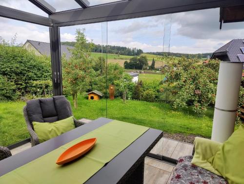 a table with an orange plate on it in front of a window at Ferienhaus Diemelsee-Sudeck in Diemelsee