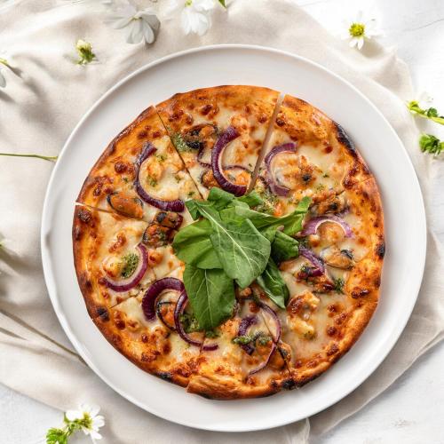 a pizza on a plate on a table at Stayso The House Hotel in Istanbul