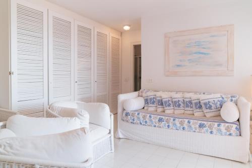 Una habitación blanca con sillas blancas y una cama. en Portisco1, en Marina di Portisco