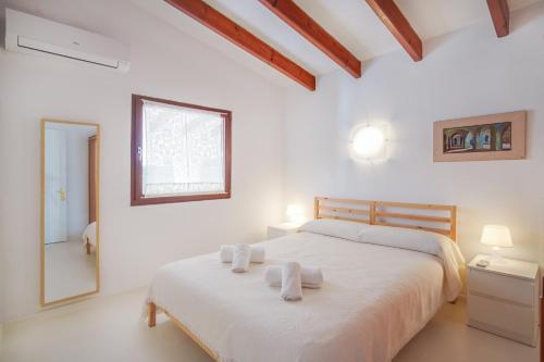a white bedroom with a bed and a mirror at Aure Villa con piscina y aire acondicionado! in Cala'n Bosch
