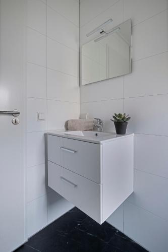 a white bathroom with a sink and a mirror at Luxe Relax Lodge Naxos in Heinkensand