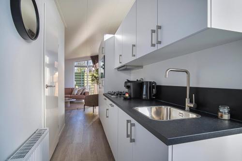 a kitchen with white cabinets and a sink at Luxe Relax Lodge Naxos in Heinkensand