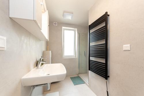 a white bathroom with a sink and a window at Beautiful apartment in city in Medlánky