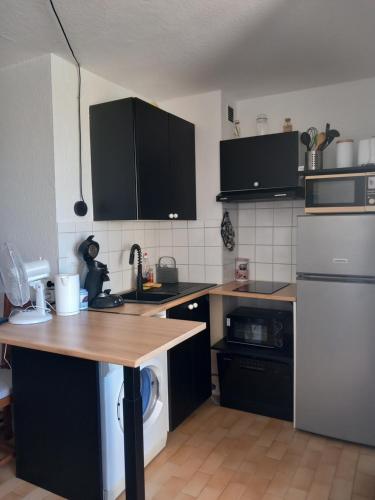a kitchen with black cabinets and a wooden counter top at T2 cabine Port-Leucate 4 personnes balcon climatisation parking in Port Leucate