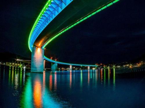 a bridge over water at night with green and blue lights at Grids Premium Hotel Kumamoto in Kumamoto