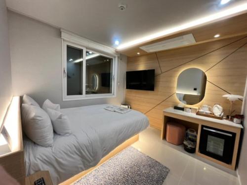 a bedroom with a bed and a mirror and a tv at Cony Ocean Suite Hotel in Jeju