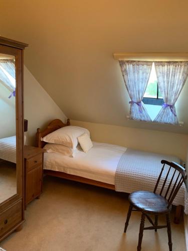 a bedroom with a bed and a chair and a window at Golf Cottage in Gullane