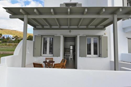 una pérgola en una casa blanca con mesa y sillas en Easy Living Tinos, en Vrachonisída Chántra