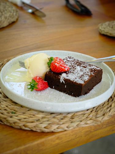 a piece of chocolate cake with strawberries on a plate at MAKAI Surf House in Ahangama