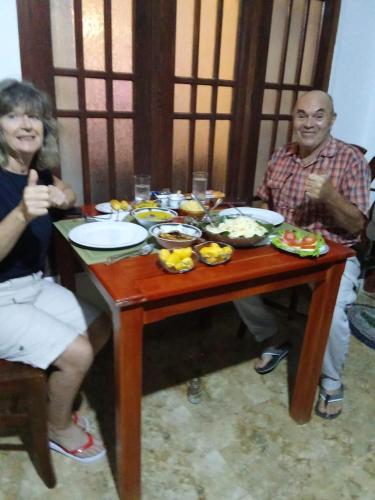 a man and a woman sitting at a table with food at Mountain Shack Homestay in Ella