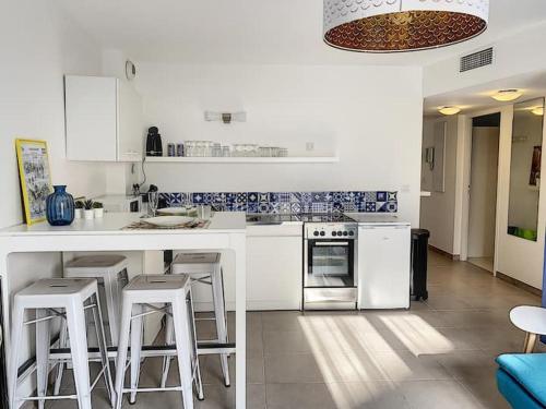 une cuisine avec des armoires blanches et des tabourets de bar dans l'établissement Bel appartement spacieux Sainte-Maxime Centre ville, à Sainte-Maxime