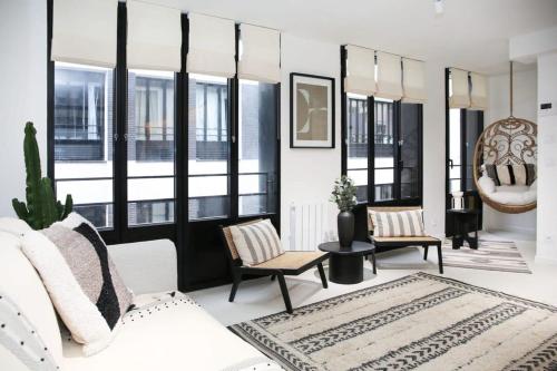 - un salon avec un canapé blanc et quelques fenêtres dans l'établissement Elegance et confort pres du Marais Cosy - 4P, à Paris