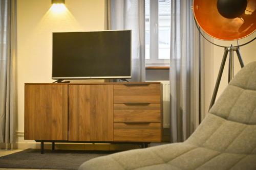 a living room with a tv on a dresser with a chair at Le Repos de l'aventurier in Mommenheim