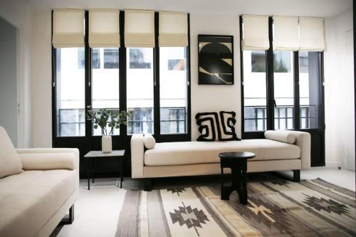 un salon avec un canapé et deux fenêtres dans l'établissement Espace et Confort en Famille - Marais a Cote - 6P, à Paris