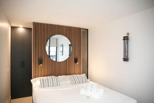 une chambre avec un lit blanc et un miroir dans l'établissement Espace et Confort en Famille - Marais a Cote - 6P, à Paris