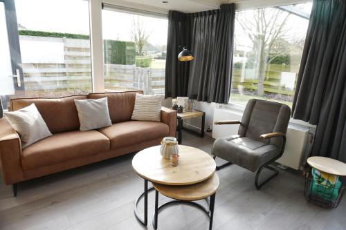 a living room with a couch and a chair and a table at Kustverhuur, Park Schoneveld, Duinroos 123 in Breskens