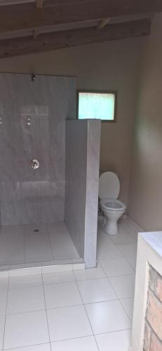 a bathroom with a toilet and a shower with a window at East Africa Safaris in Chizavane