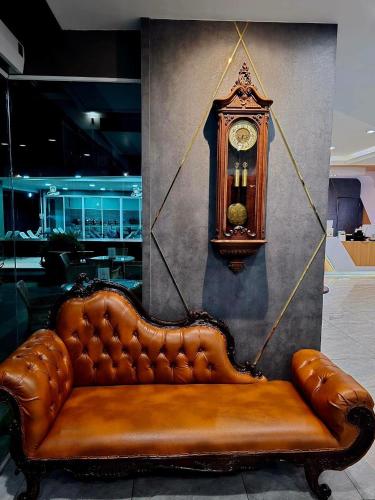 a brown leather couch with a clock on a wall at LHC HOTEL AND RESORT in Pattaya Central