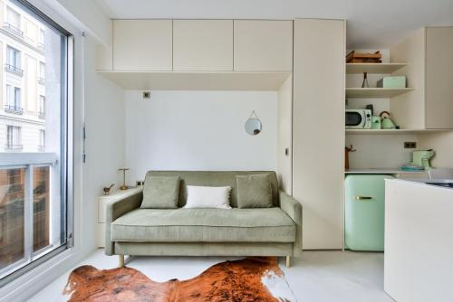 un salon avec un canapé et une fenêtre dans l'établissement Cosy studio near Georges Brassens Parc, à Paris