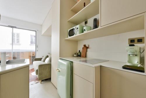  La cuisine est équipée de placards blancs et d'un réfrigérateur. dans l'établissement Cosy studio near Georges Brassens Parc, à Paris