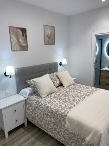 a white bedroom with a bed and a nightstand at El salon de los abuelos in Trescasas