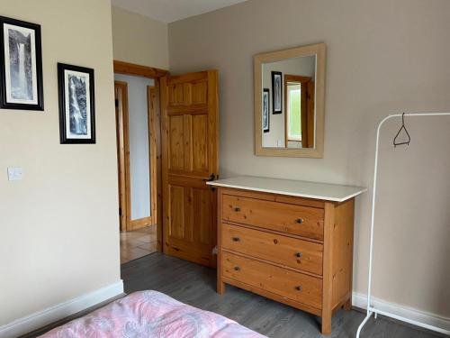 a bedroom with a wooden dresser and a mirror at Ballygarrett Holiday Home by Trident Holiday Homes in Ballygarrett