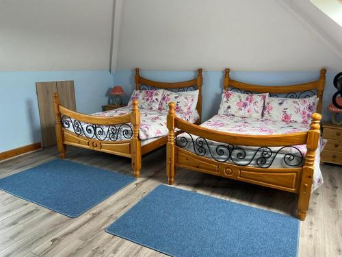 two twin beds in a room with wooden floors at Ballygarrett Holiday Home by Trident Holiday Homes in Ballygarrett