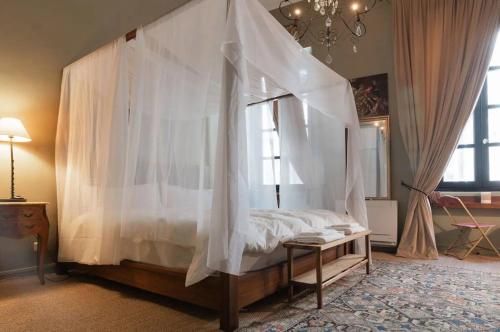 une chambre avec un lit à baldaquin avec des rideaux blancs dans l'établissement Charme et confort, à Avignon