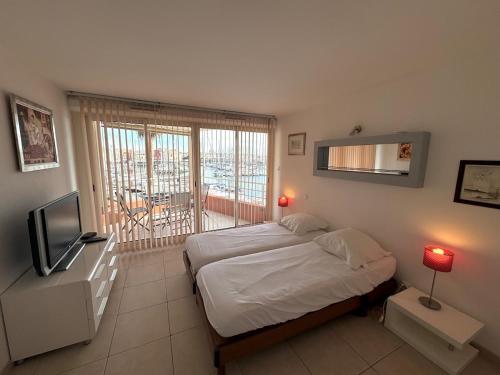 une chambre avec un lit et une télévision et un balcon dans l'établissement Appartement - Cap d'Agde, au Cap d'Agde